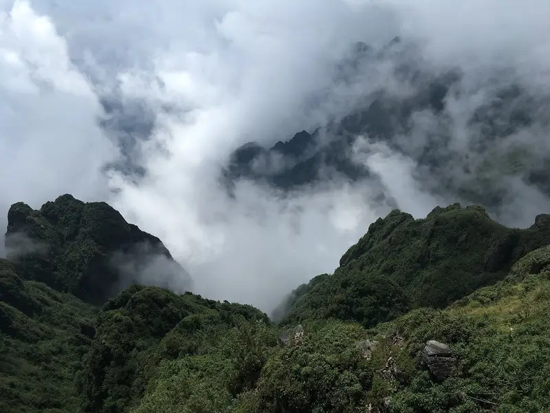 Cloud spilling between steep green ridges below the summit of Fansipan